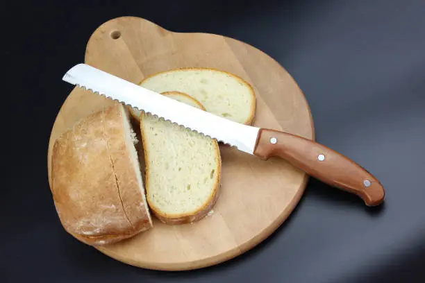 Knife is cutting a loaf of bread into slices. Seed bread, homemade bread,cutting bread