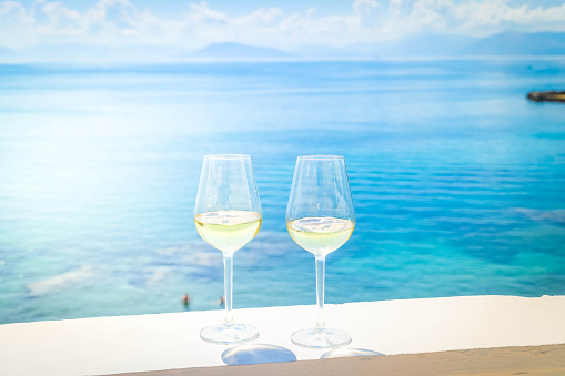 Two glasses of white wine with Corfu summer seascape in background