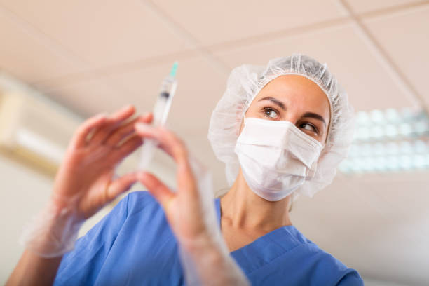 Young nurse in the treatment room prepares a syringe for injection, filling in with medicine