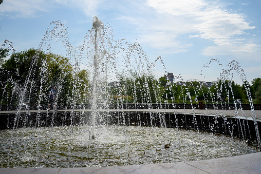 fountain in city park against blue sky with white clouds for wallpaper and design