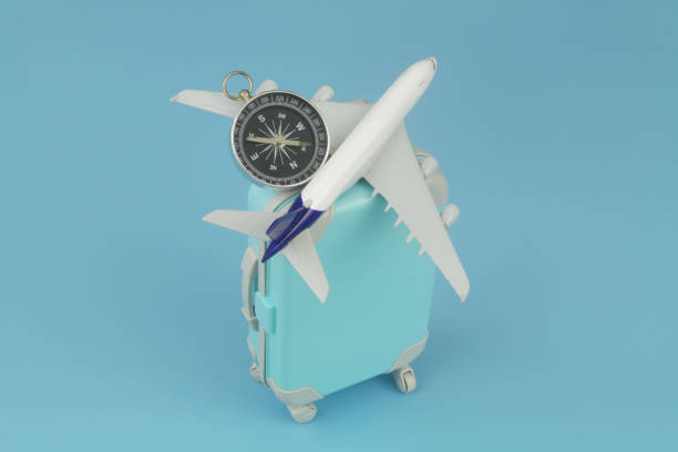 istock Airplane model and compass with travel suitcase on blue background. 1414988418
