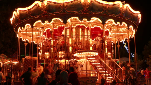 People riding a carousel at night in an amusement park