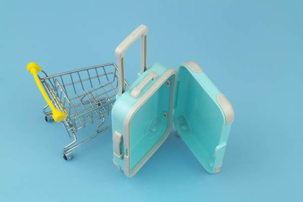istock Shopping cart with suitcase on blue background close up. 1414989477