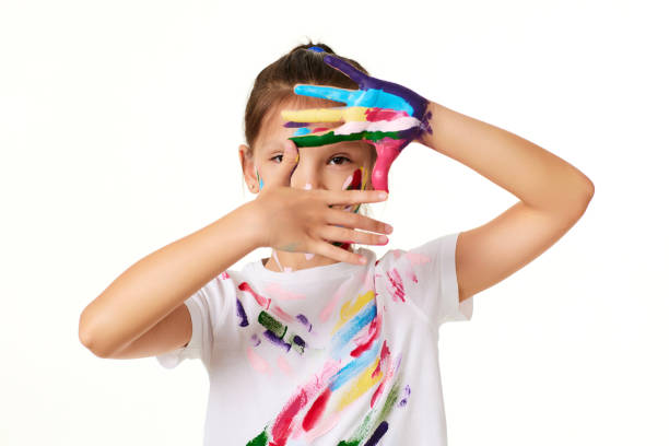 niña mira a través de las manos pintadas en pintura colorida - confusion single object human finger one person fotografías e imágenes de stock