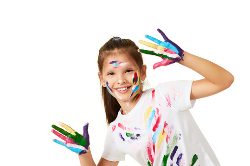 happy little child girl showing hands painted in colorful paint isolated on white background.