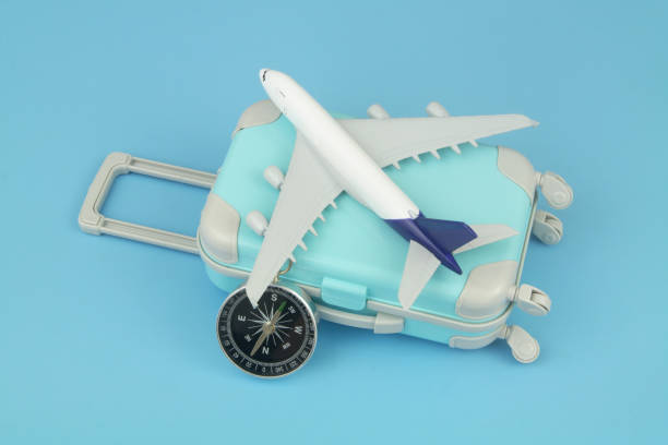 istock Airplane model and compass with travel suitcase on blue background. 1414991374