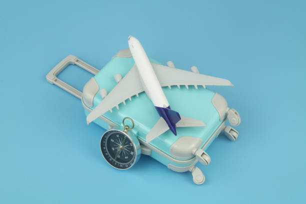 istock Airplane model and compass with travel suitcase on blue background. 1414991547