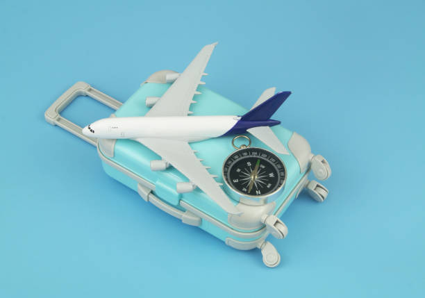 istock Airplane model and compass with travel suitcase on blue background. 1414991550