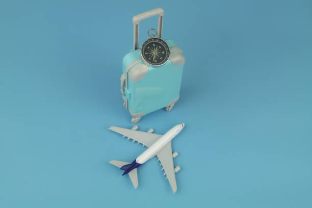 istock Airplane model and compass with travel suitcase on blue background. 1414991752