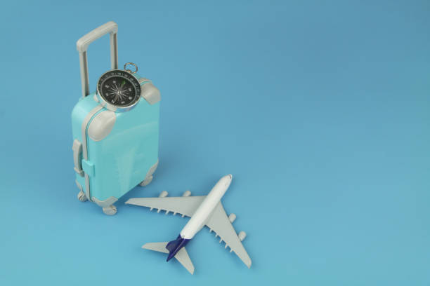 istock Airplane model and compass with travel suitcase on blue background. 1414991927