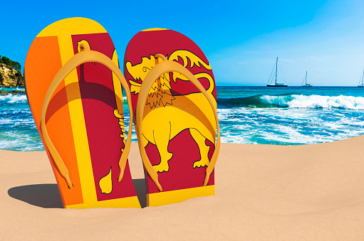 Flip flops with Sri Lankan flag on the beach. Sri Lanka resorts, vacation, tours, travel packages concept. 3D rendering