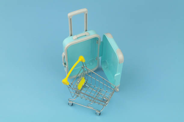 istock Shopping cart with suitcase on blue background close up. 1414992151