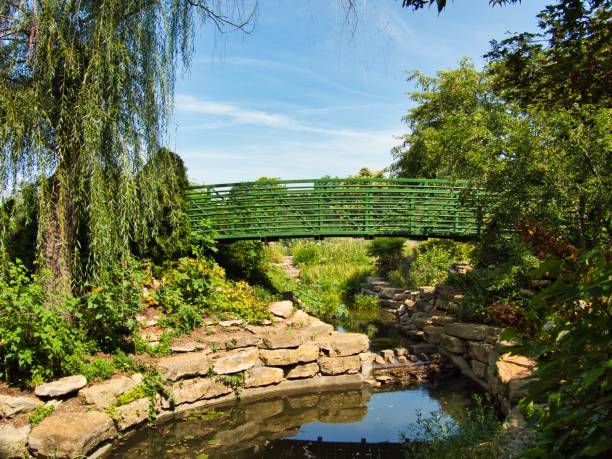 istock Green Bridge Crossing Beautiful Flower Garden 1414993675