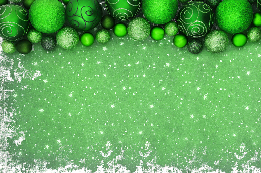 Christmas green sparkling bauble tree decorations on grunge background. Festive border composition for the holiday season.