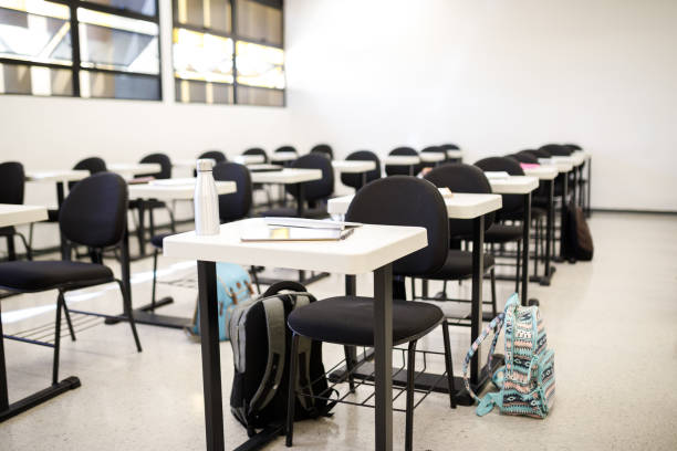 istock Empty classroom with materials over the desks and backpacks on the floor 1414996868