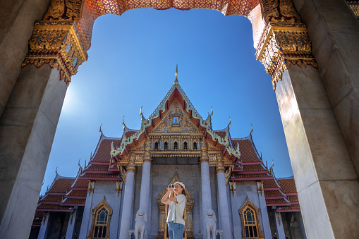 Asian female tourists take pictures of beautiful temples at Bangkok,  Thailand.