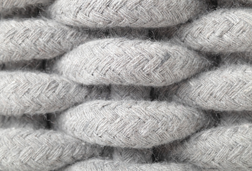 Macro of light grey large weaving pattern made of woven cotton rope. Textile background texture or surface. Selective focus.