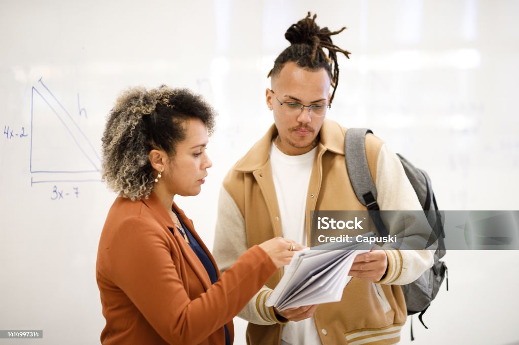 Professor explaining topics to student that is holding a notebook going back to school Professor Stock Photo