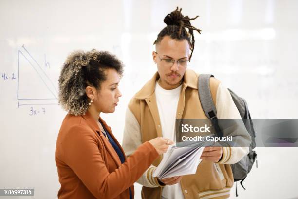 Professor Explaining Topics To Student That Is Holding A Notebook Stock Photo - Download Image Now