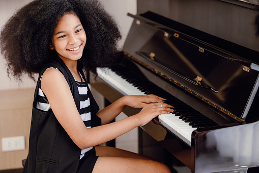 African black children playing piano music instrument happy smiling.