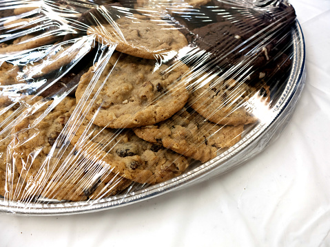 Many cookies on a plate under plastic wrap for a fresh dessert