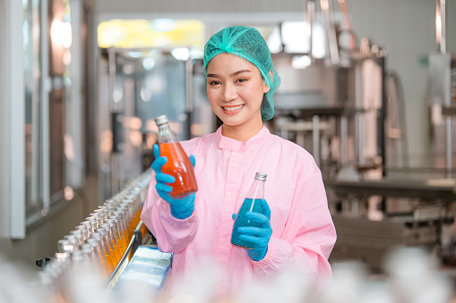 Asian woman employee working Food quality control in Factory and worker inspecting production line beverage tanker in of dairy factory Concept food industry
