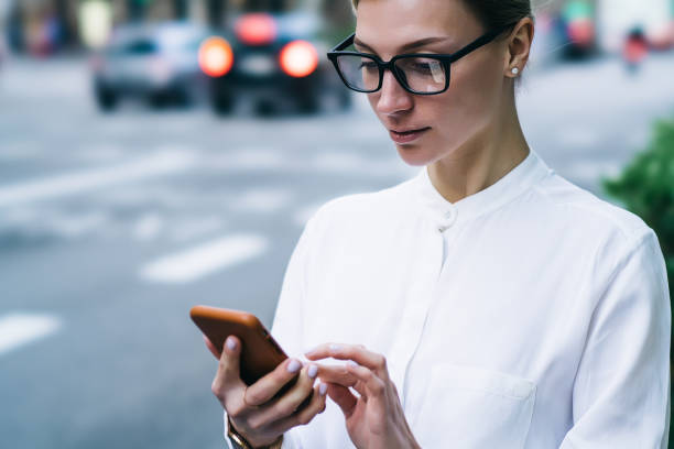 istock Focused young female messaging on smartphone in street 1415001907