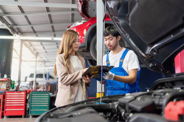 Pretty woman explain the problem of car to the professional vehicle maintenance man in uniform at garage. Car repair service concept. Customer feeling happy in auto service center. Pretty woman explain the problem of car to the professional vehicle maintenance man in uniform at garage. Car repair service concept. Customer feeling happy in auto service center. sign human hand pointing manual worker stock pictures, royalty-free photos & images