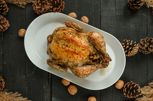 Delicious homemade roasted chicken or turkey ready to be carved. Thanksgiving or Christmas flat lay composition on wooden table.
