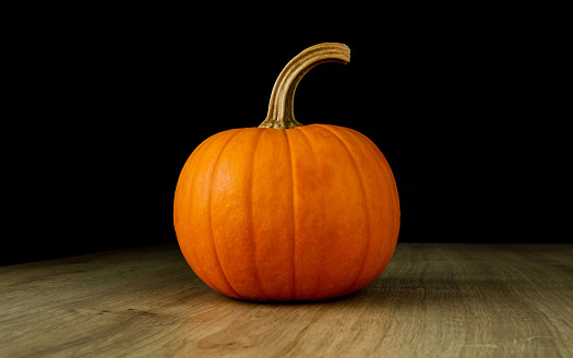 Small decorative autumn pumpkin on a wooden table.