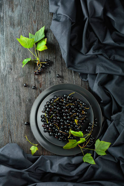 Black currant with leaves on a old wooden table. stock photo