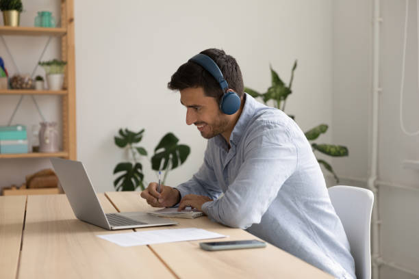 istock Man seated at desk e-learning use videocall app and laptop 1415007996