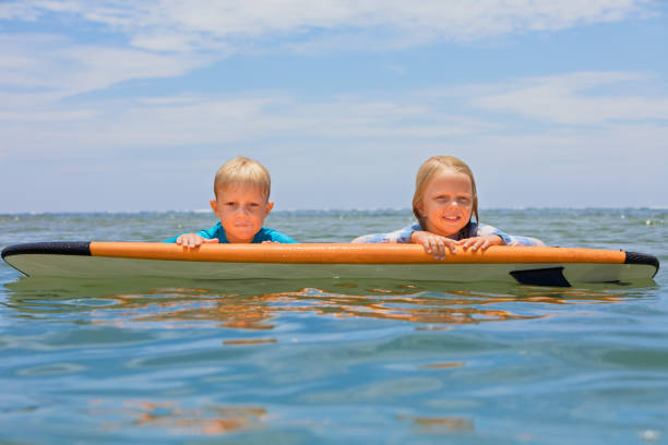 istock Two young surfers ride with fun on one surfboard 1415008492