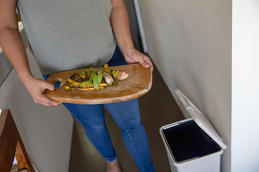 High angle view shot of unrecognizable woman throwing organic food waste into trash bin