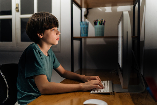 Boy using desktop computer at home at night