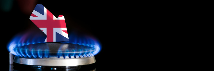 Decreased gas supplies in United Kingdom. A gas stove with a burning flame and an arrow in the colors of the United Kingdom flag pointing down. Concept of crisis in winter and lack of natural gas