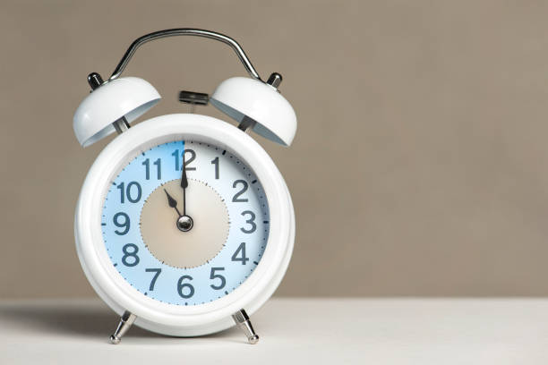 istock Eleven o'clock on the alarm. A white alarm clock is on a white table. The clock hand points to 11 o'clock. Time to change to summer or winter time. Set an alarm for 11:00 or 23:00. copy space 1415019532