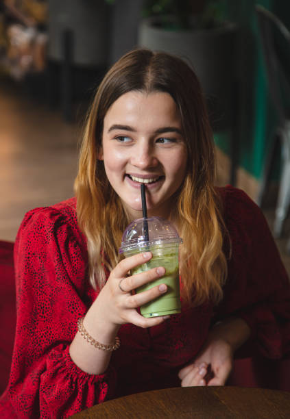 istock A young woman in a cafe drinks a green drink ice latte. 1415019845