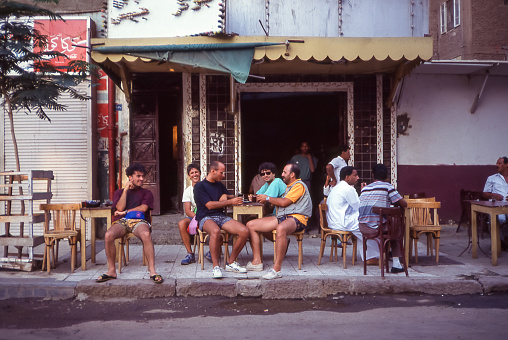 Aswan, Egypt - aug 12, 1991: in a street in the old part of Aswan a small group of people sit at the table of a simple Egyptian bar.