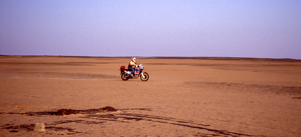Nubian desert, Egypt - aug 13, 1991: a motorcyclist transits on a sandy track in the Nubian desert in the direction of Abu Simbel, in the extreme south of Egypt