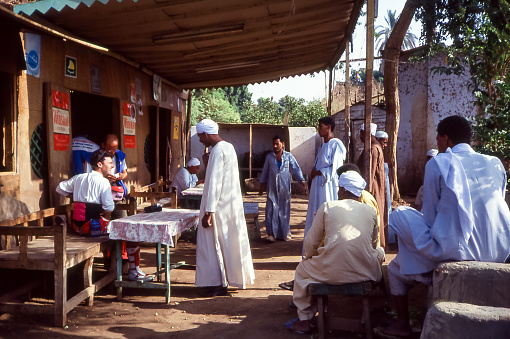 old man in an African village with shacks with thatched roof