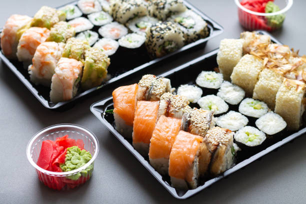 Sushi roll in plastic box for take away background Big sushi rolls set in black plastic box for take away on gray background sushi plate stock pictures, royalty-free photos & images