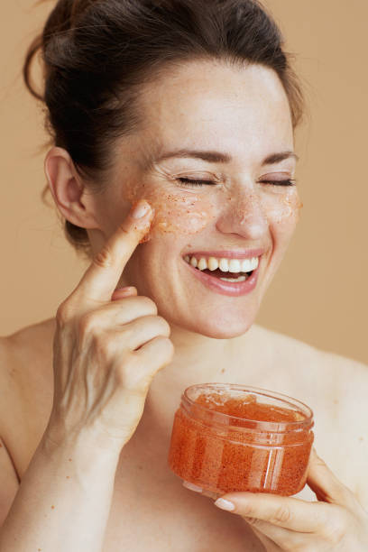 smiling modern 40 years old woman with face scrub stock photo