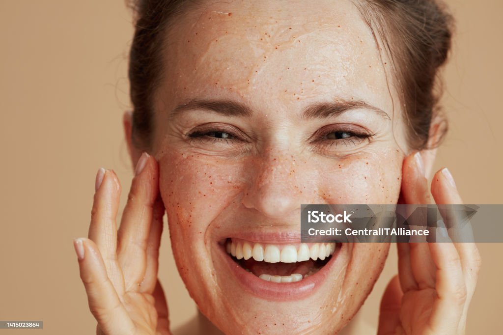 happy modern woman with face scrub against beige background happy modern woman with face scrub against beige background. Exfoliation Stock Photo