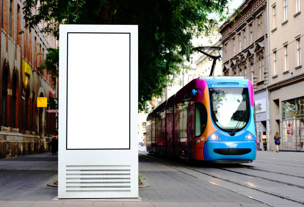 composite collage image of lightbox ad panel at a tram stop. background for mock-up composite image collage of lightbox ad panel and a tram stop. background for mock-up. empty milky white poster ad and advertising display glass.  aluminum frame structure. street perspective with colorful tram and trees. urban background. bus hungary stock pictures, royalty-free photos & images