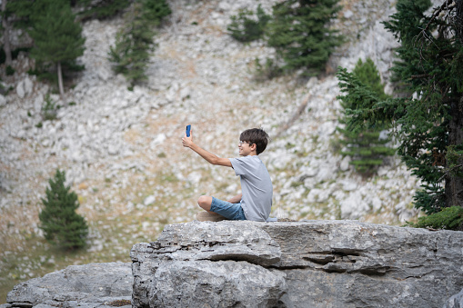 Young boy taking selfie on top of mountain.