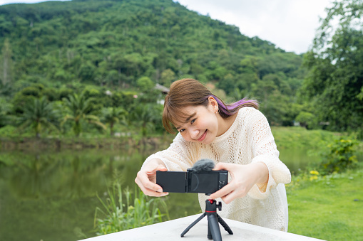 Young Asian YouTuber filming beautiful scenery on her solo vacation trip.