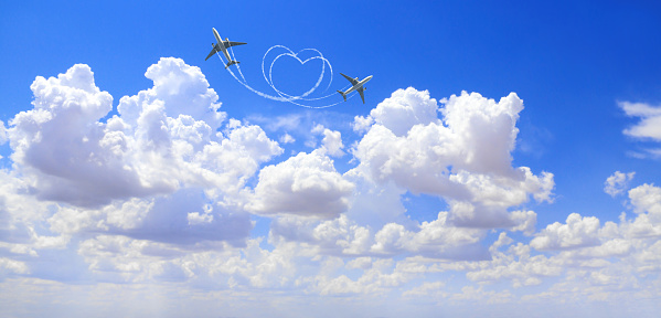 Horizontal nature background with two aircrafts draw a heart in the sky. Flight route of aircraft in shape of a heart. Love concept for traveling the world