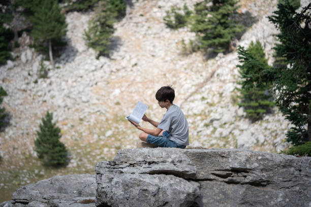 Young boy reading book outdoor on mountain