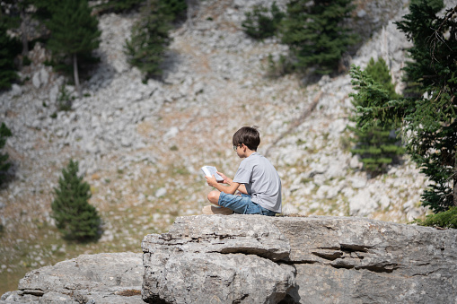 Young boy reading book outdoor on mountain